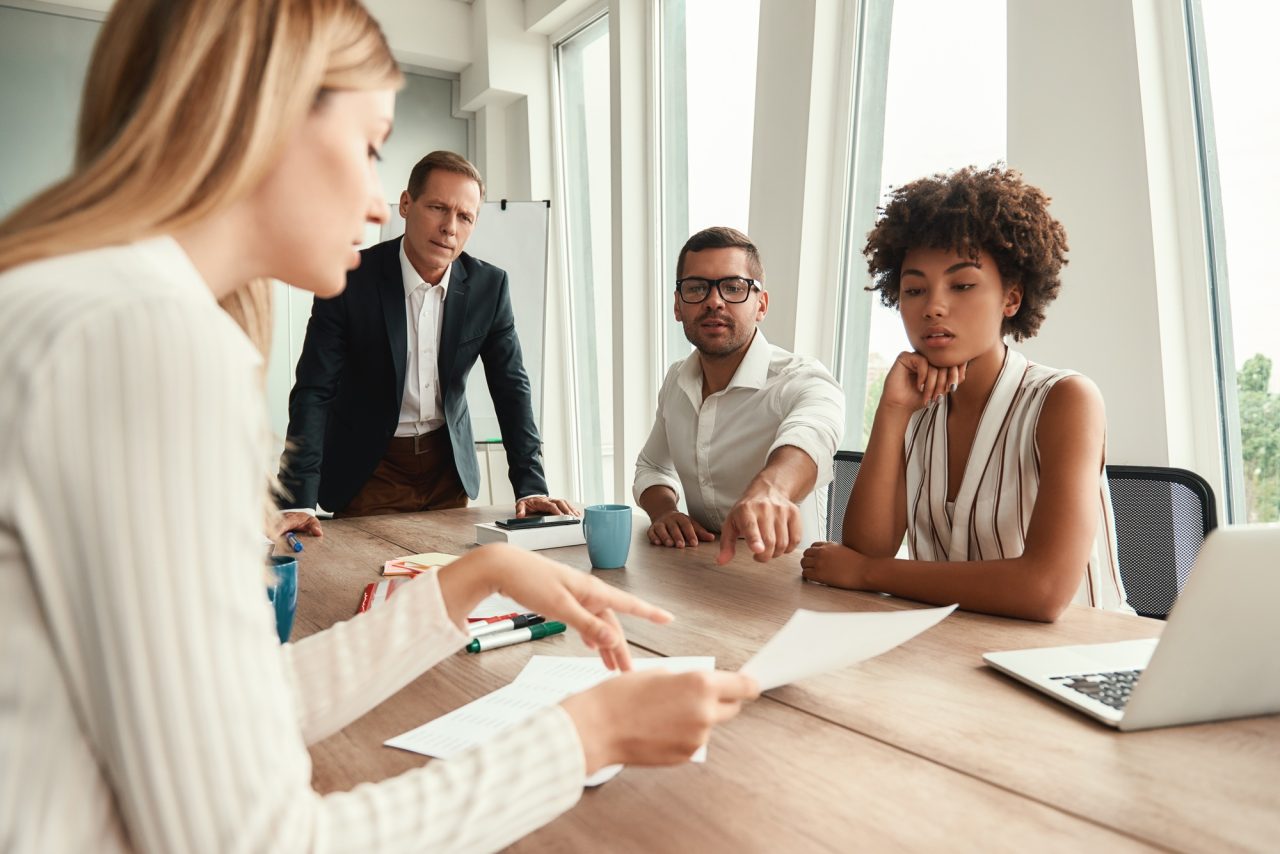 Business meeting group of young business people looking at documents and discussing something while.jpg